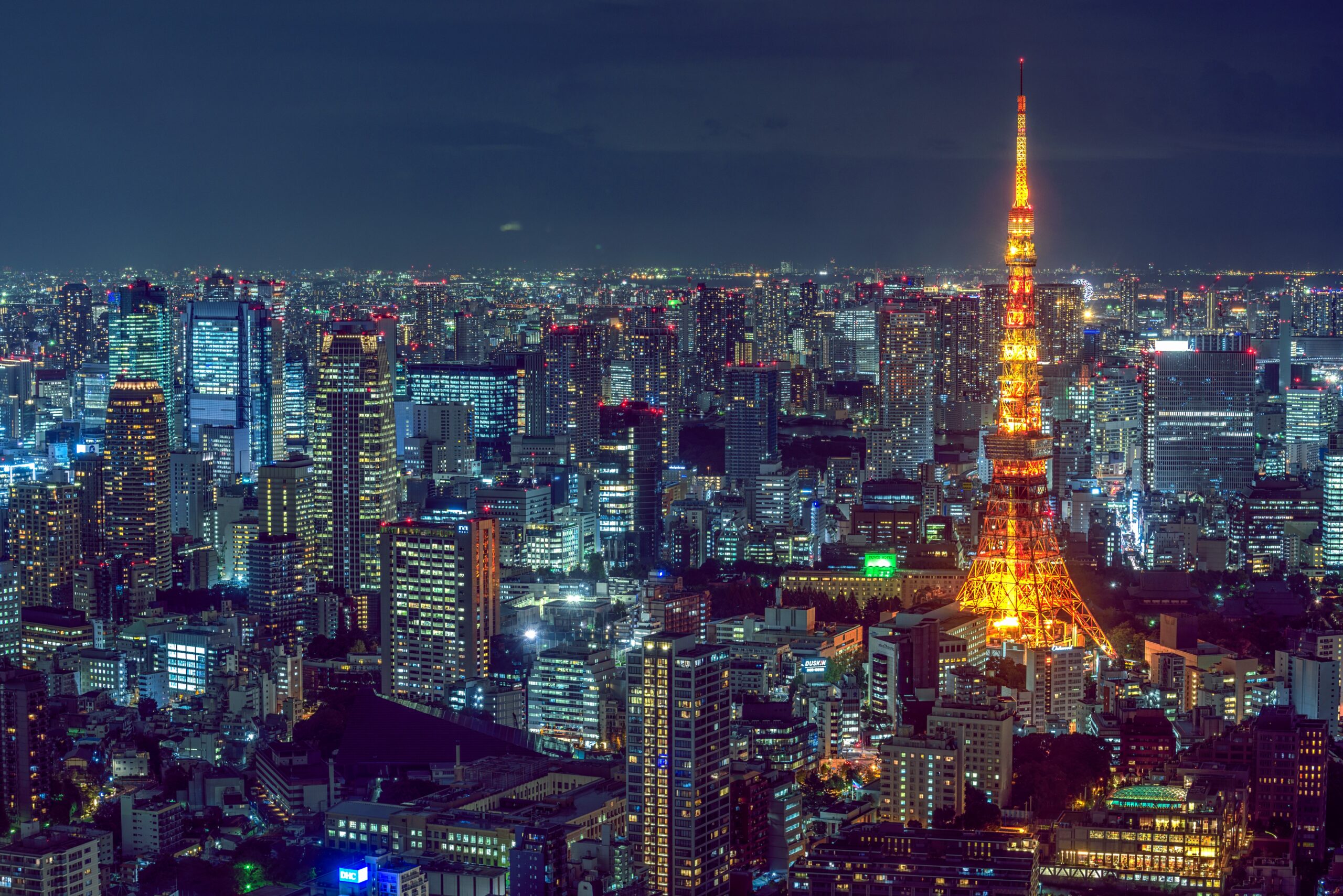 A beautiful aerial shot of modern city architecture with an illuminated tower on the side